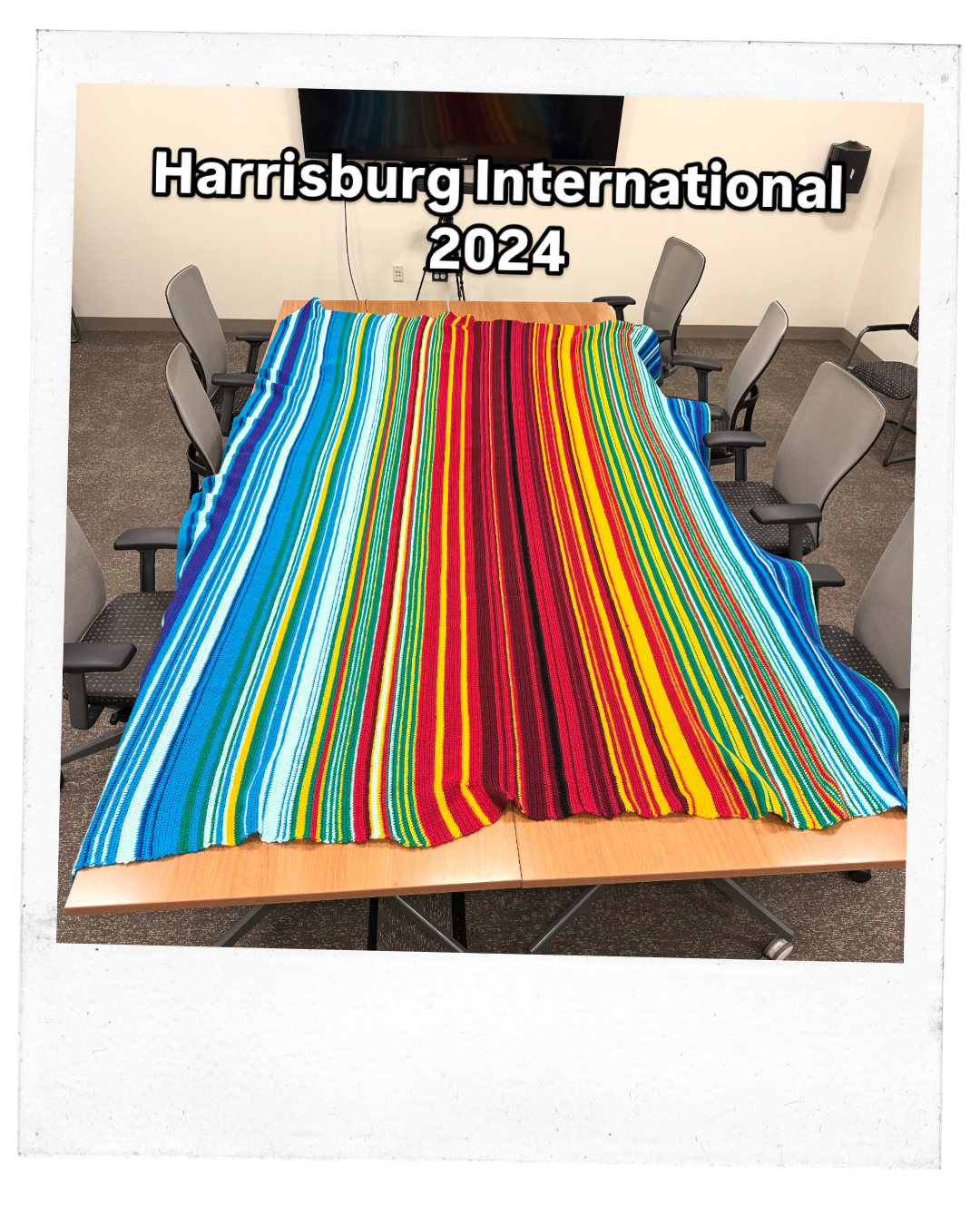 A large king sized blanket consisting of lines of shades of blues, yellows, and reds representing temperatures lays on a large table.