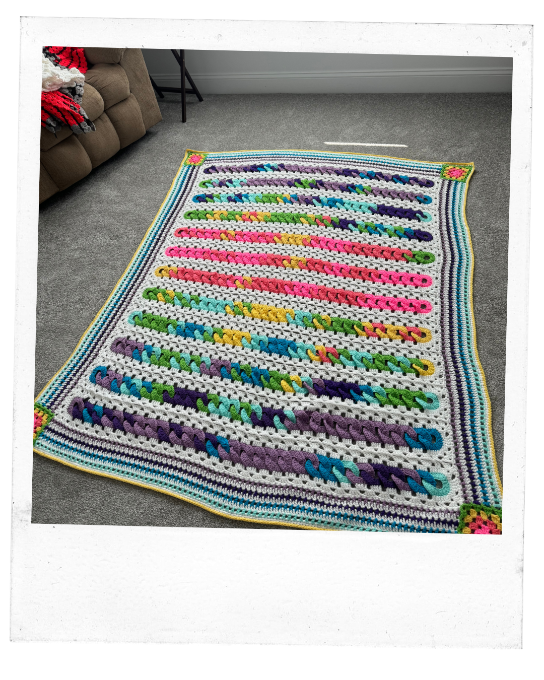 Polaroid of a colorful blanket with large crochet loops of bright colors in lines