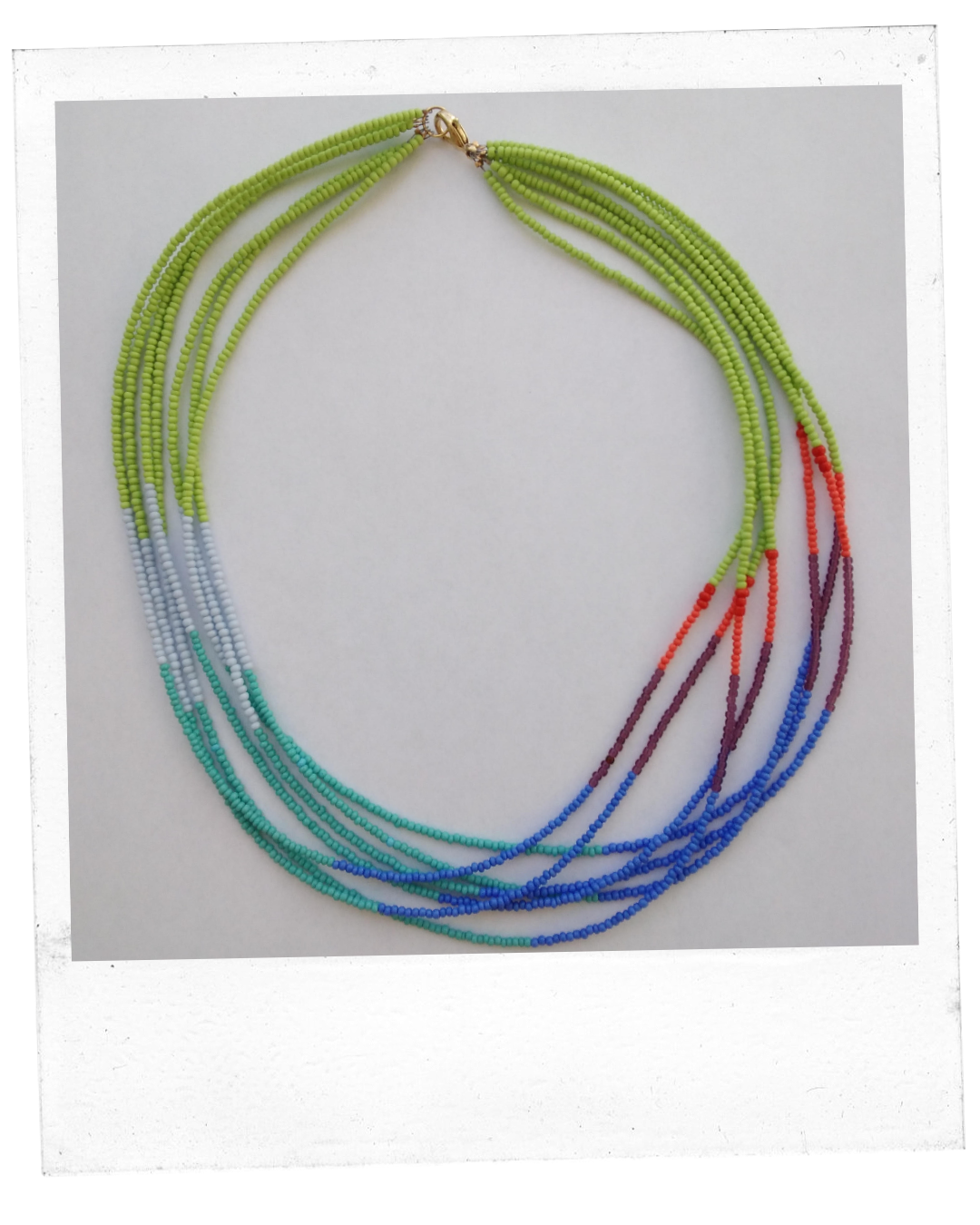 A beaded necklace of several strings comprised of small beads in shades of greens, blues, and reds