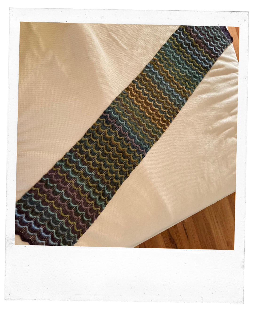Temperature scarf, consisting of scalloped lines of varying shades of  gold, yellows, green, blues. 