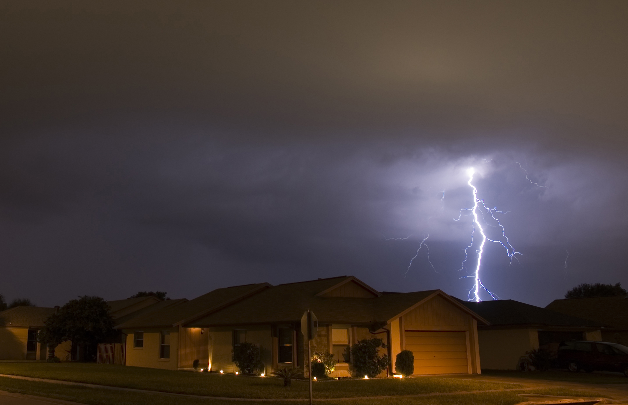 Lightning strikes in the night near family houses stock photo