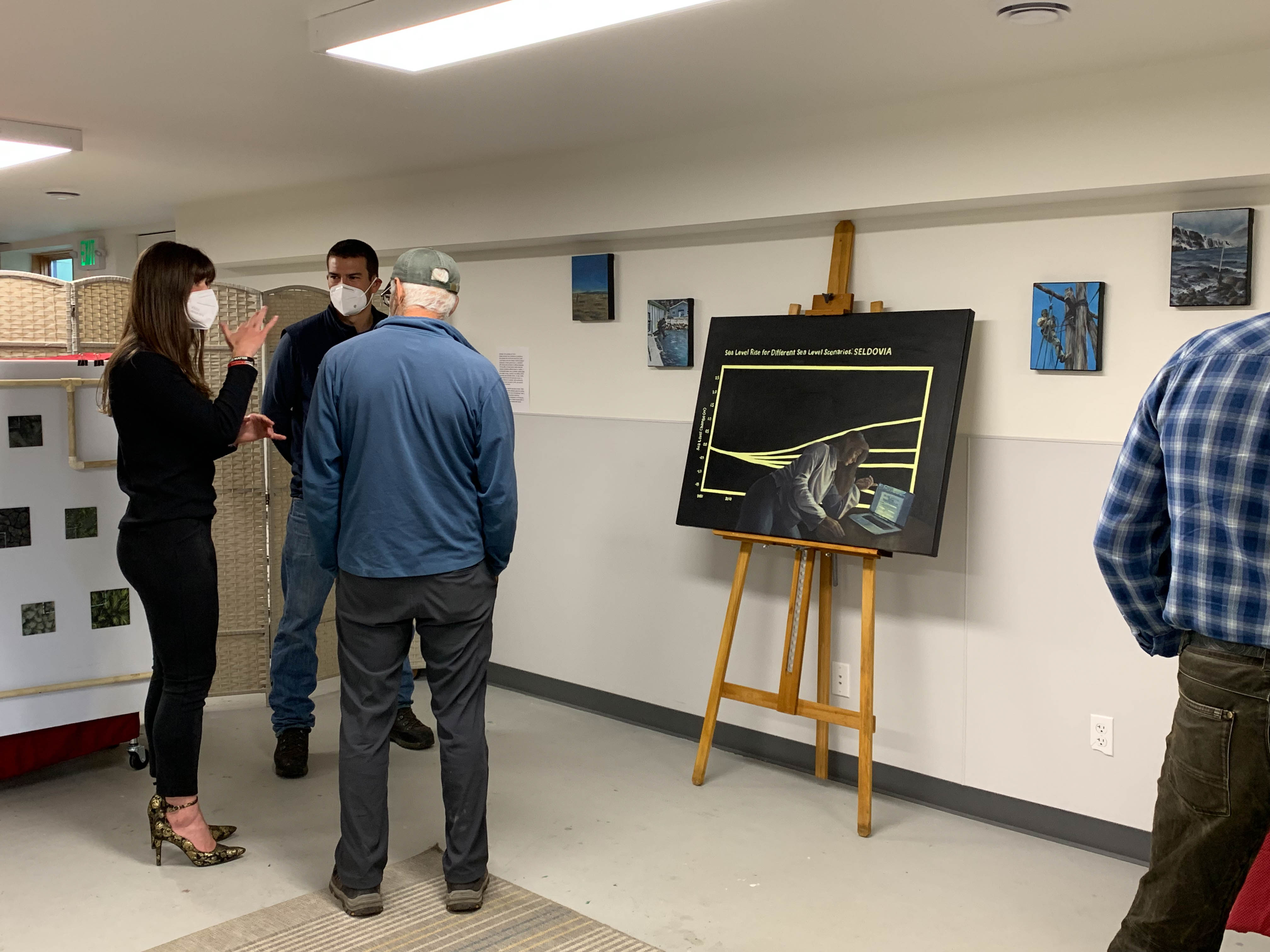 Kate is captured mid-gesture as she talks to two people at her art show.