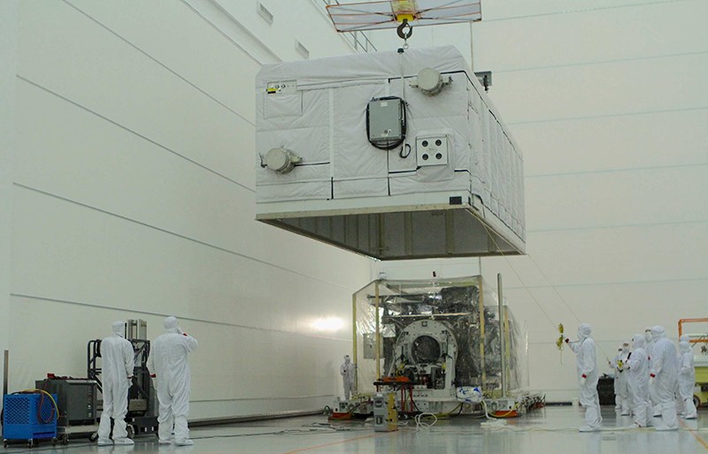 Staff in protective clothing unwrap the GOES-R satellite in the “clean room.” The satellite has many parts that are sensitive to contamination, so engineers and technicians wear special clothing to protect the satellite in a room that is designed to keep it safe until it is encapsulated on top of the rocket for launch. 
