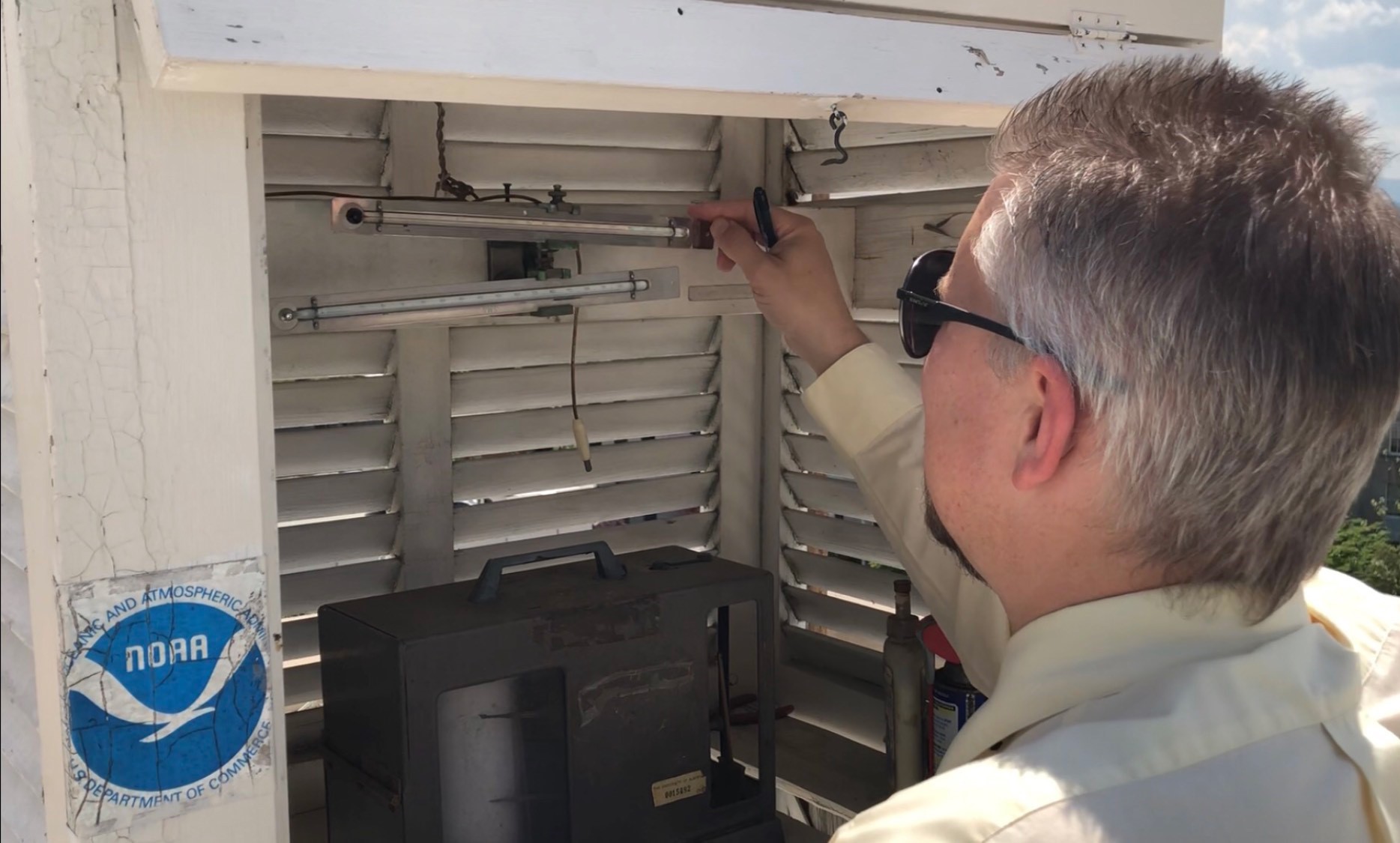 A NOAA employee in Asheville, North Carolina resets the index on a pair of minimum/maximum thermometers in a NOAA weather station. The index in the fluid marks the high and low of the day. 