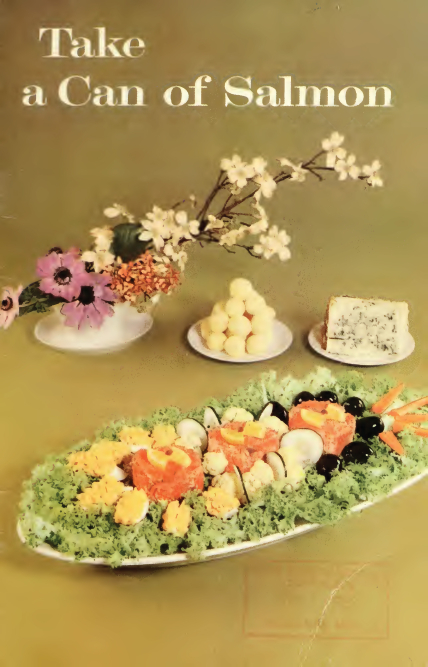 The front cover of Test Kitchen Circular No. 60, from 1960. The title reads, "Take a Can of Salmon" in white text and there is an elaborate salmon dish on the background, accompanied by small plates of butter and cheese, as well as a vase of flowers.