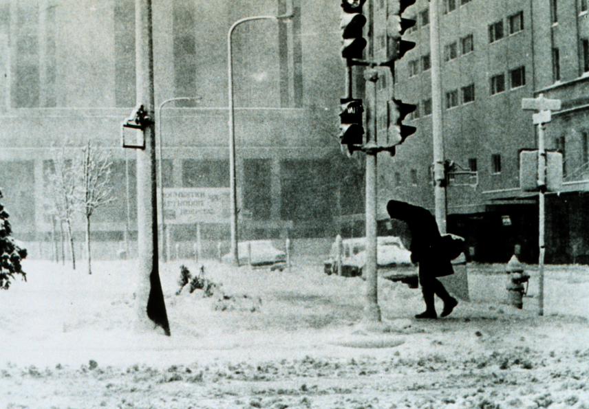 Black and white photo of a person bending into the wind during a blizzard in Rochester, Minnesota. March 24, 1966.