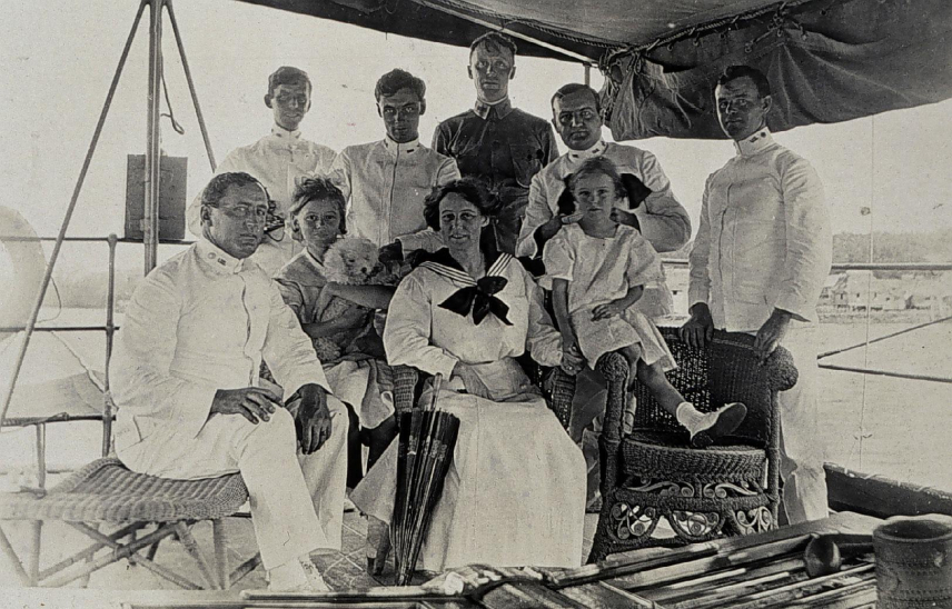 USC&GSS Marinduque crew members, family, and pet miniature poodle poses together on the ship's deck.