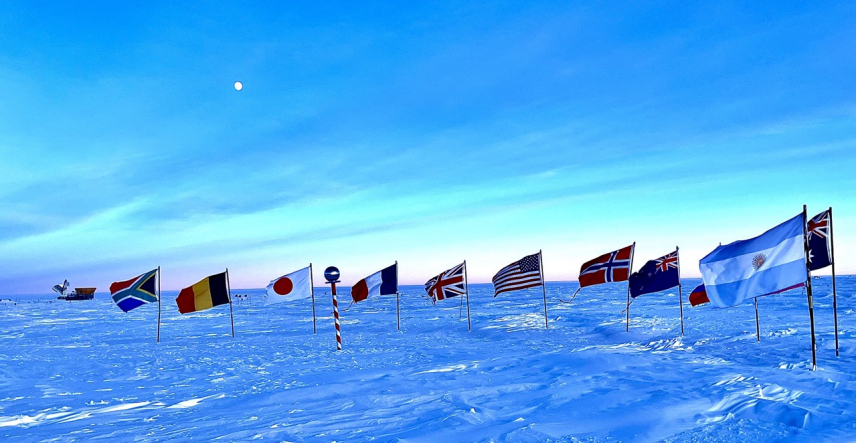 A green sky and nearly full moon above the Dark Sector and Ceremonial South Pole. The Dark Sector is a designated area where light and electromagnetic interference are minimized to support sensitive scientific instruments.