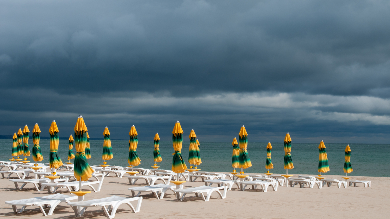 Closed umbrellas on a beach with a storm approaching