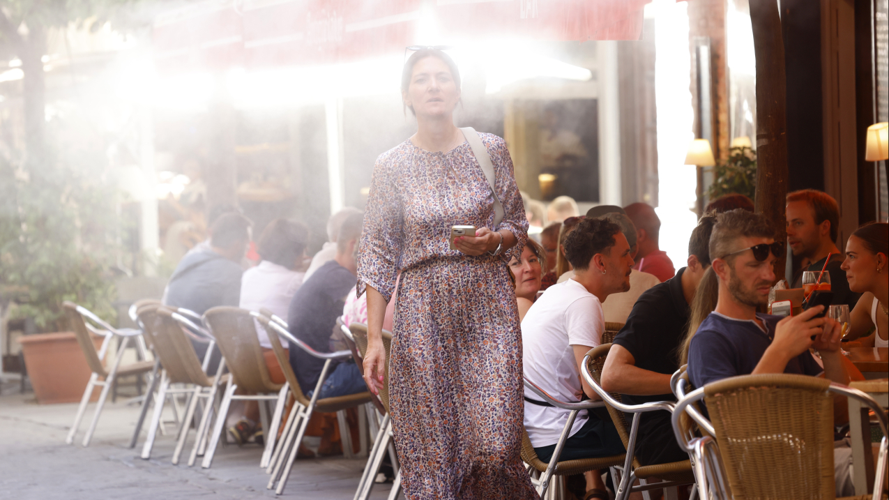 SEVILLE, SPAIN - AUGUST 21: A person walks past a place of business cooled by water vapor during a heatwave on August 21, 2023. The city — the hottest major metropolitan area in continental Europe — baked under Europe’s second-warmest August and third-warmest summer on record.