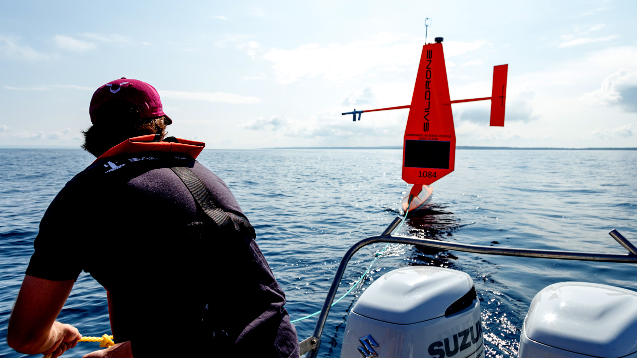 Photo of Vehicle assembly and service technician Josh Keller unties Saildrone 1084 from the tow line in Lake Michigan to deploy it for a 2023 U.S. Coast Guard Great Lakes Fisheries survey.