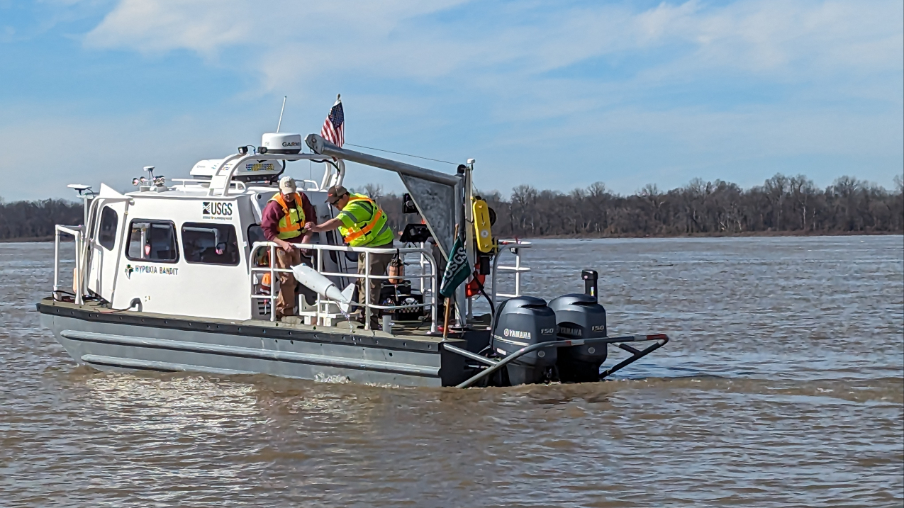A photo of USGS vessel "Hypoxia Bandit" on the Mississippi River in Vicksburg in early 2024.  USGS scientists are using a US-D-96 sampler to collect sediment and water-quality samples from the river.  Credit: Lane Simmons (USGS Lower Mississippi Gulf Water Science Center)