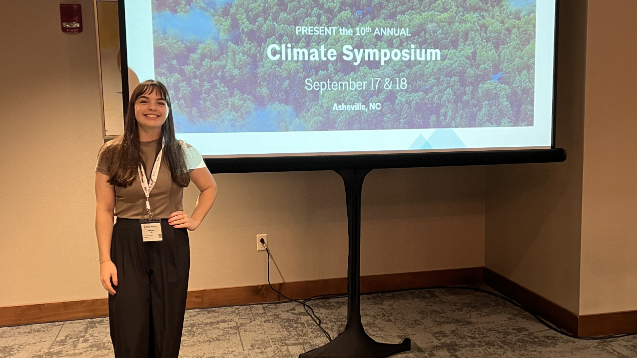 Morgan Stahl stands in front of a slide from the Climate Symposium at the American Institute of Architects (AIA) Aspire Conference