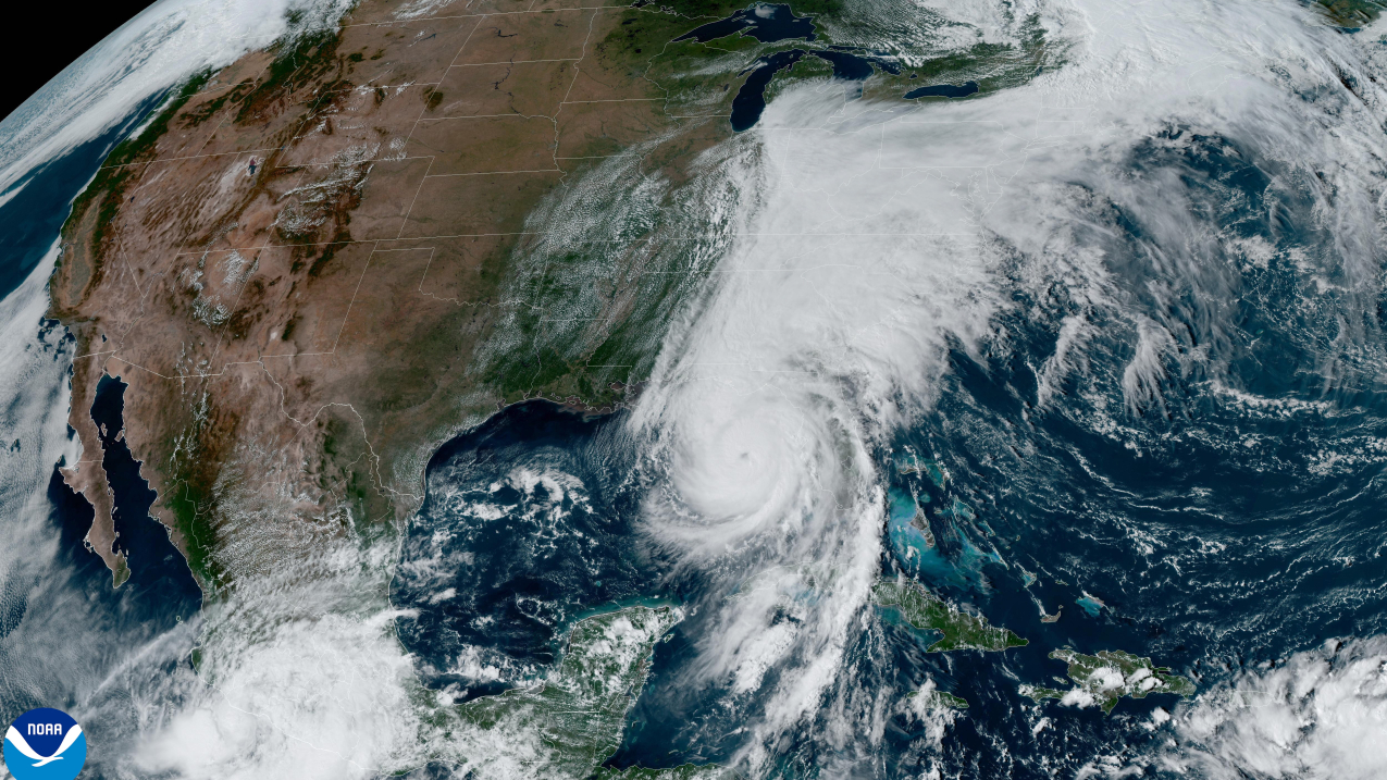 A satellite image shows the continental United States, with a large swirling hurricane covering Florida and cloud cover expanding over the eastern seaboard. 