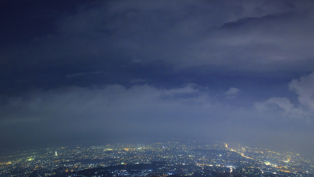Aerial views over urban, night-time landscape.