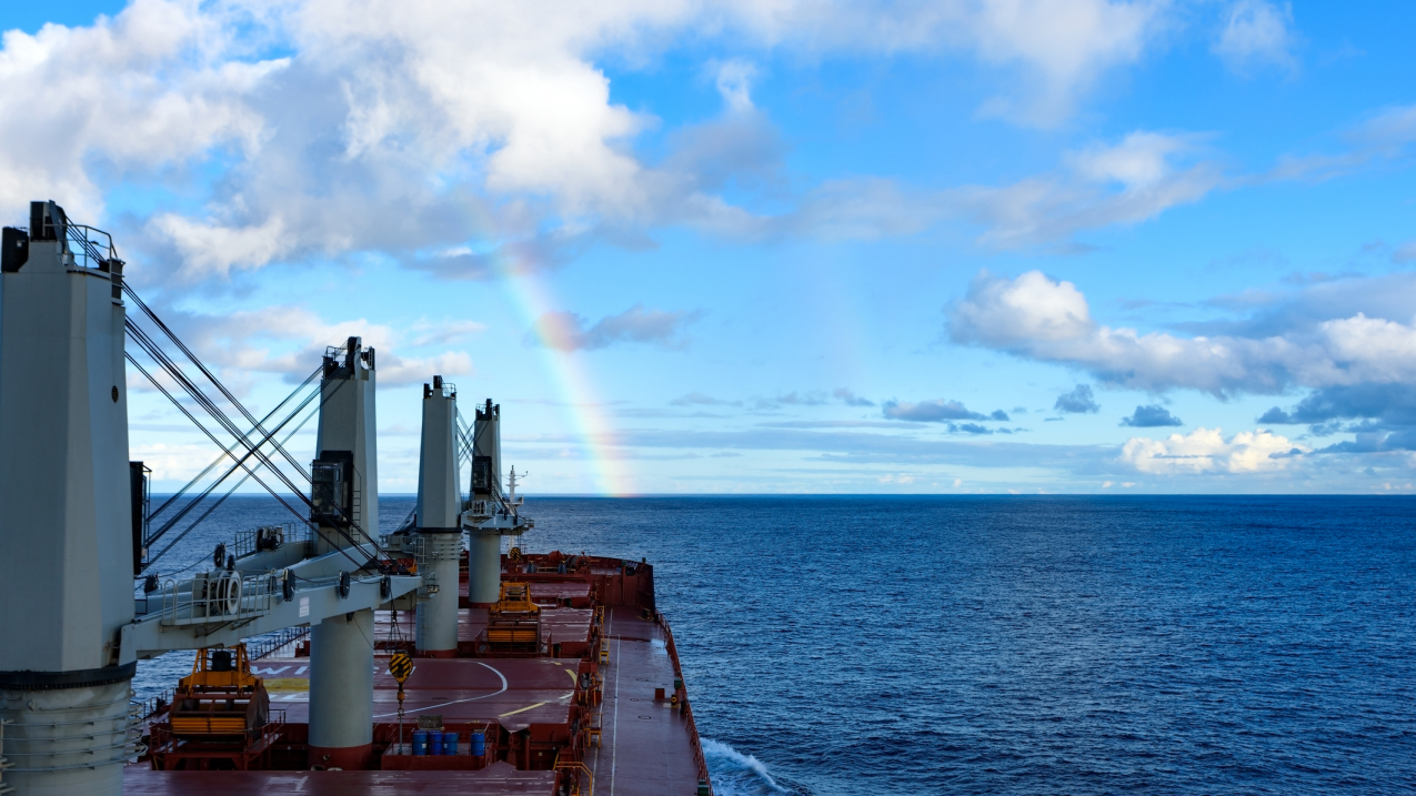 A commercial cargo ship sails into calm waters