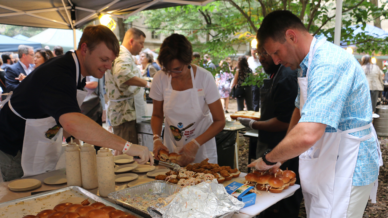 NOAA Officers' Family Association; Capt. Rick Brennan, Tracey Brennan, and Capt. Chris van Westendorp serving up wild blue catfish po’ boys with green papaya and cabbage slaw. Fish donated by J.J. McDonnell Seafood.
