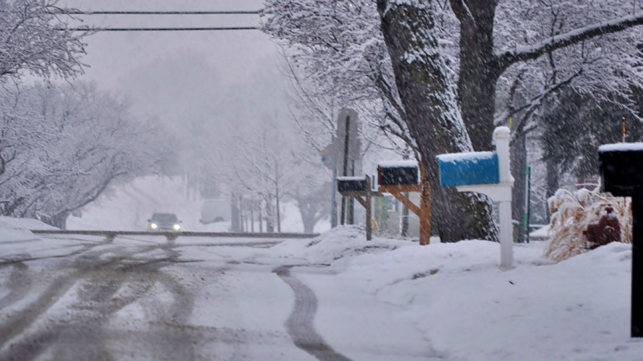 A car drives on a snow-covered local road in suburban northwest Chicago in 2018.