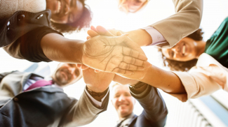 Group of business people creating a huddle. (shutterstock)