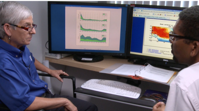 Two people sitting in front of a computer.