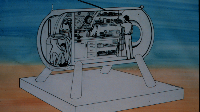 A drawing of the HYDROLAB, showing a cross section of the inside. Two people are inside the Hydrolab, one at the lab and the other in the moon pool.