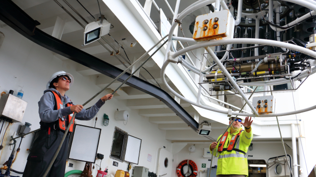 Image showing professional mariners Elan Sprouse and Ed Williams deploy equipment used to measure the seawater’s salinity, temperature and depth from NOAA Ship Reuben Lasker.