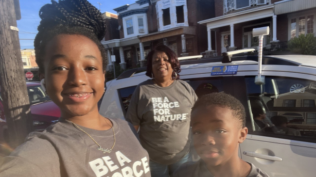 Photo showing Jayla Gardner snaps a photo of herself, Jacqueline Jones and Jaden Gardner next to the car with a heat sensor attached to it that they used to gather heat data in Philadelphia as part of the NOAA-supported 2022 Urban Heat Island Mapping Campaign.