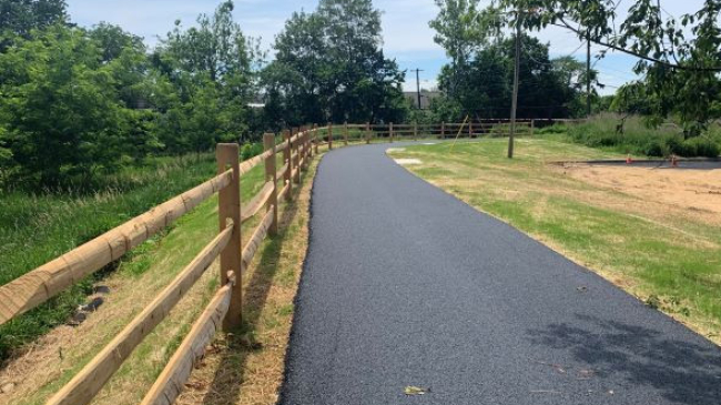 A path curves to the right with grass and trees on either side.