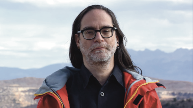 Dr. Sim Aberson stands in front of a beautiful vista with distant mountains in the background.