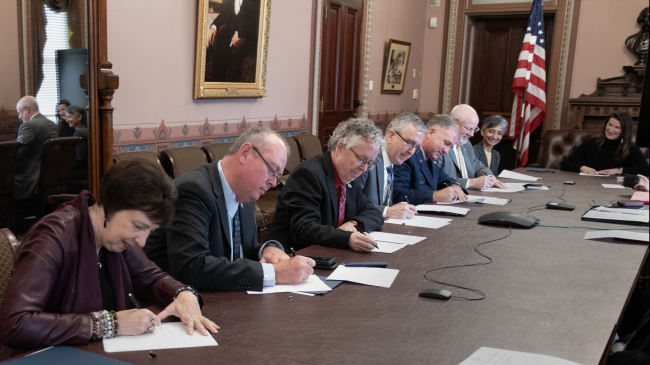 Photo showing Signing of the Memorandum of Agreement for Space Weather Research-to-Operations-to-Research Collaboration, Eisenhower Executive Office Building, Washington, D.C., Dec. 7, 2023. Left to right: NASA Nicola Fox, Ph.D., NOAA Ken Graham, NOAA Stephen Volz, Ph.D., NSF Timothy Patten, Ph.D. (on behalf of Alexandra Isern, Ph.D.), DAF Major General Mark Slocum (on behalf of Lieutenant General James C. Slife), and DAF Dr Joel Mozer (on behalf of Lisa Costa, Ph.D.).