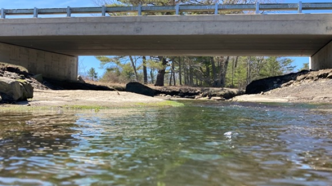  A bridge over a shallow river and rocks on a sunny day