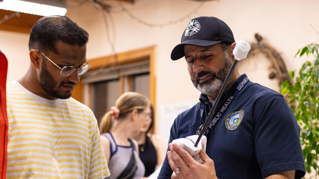 Photo of Raed Mansour showing Ashwin Sunderraj how to use a heat sensor for Chicago’s July 28, 2023 urban heat island mapping campaign (Image credit: 2023 Chicago Urban Heat Island Mapping Campaign)