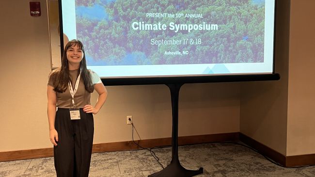 Morgan Stahl stands in front of a slide from the Climate Symposium at the American Institute of Architects (AIA) Aspire Conference