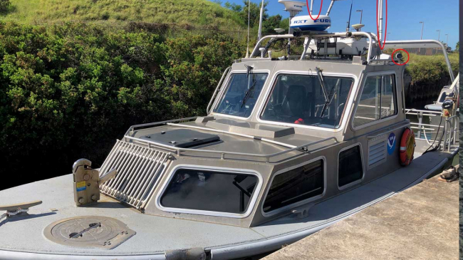 An autonomous survey launch (RA-3). Red circles drawn over photo of vessel identify newly installed radios and cameras for autonomous (unmanned) operation.