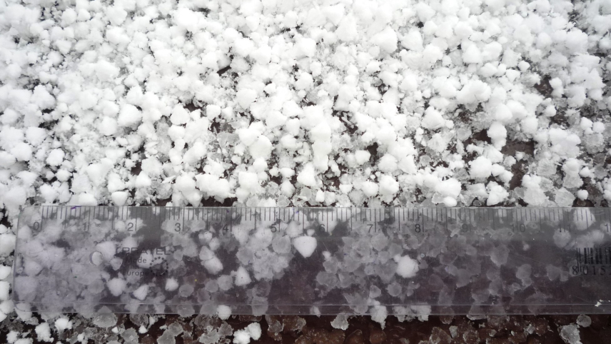 Appears to be irregular spheres of snow, each smaller than about five millimeters. The pellets look soft to the touch and below the top layer, they look to be melting into an icy slush.