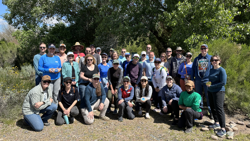  A group of people posing outdoors surrounded by green trees.