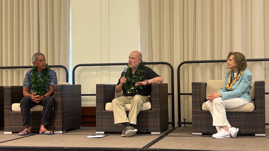 Three adults sit on a stage in a panel discussion. 