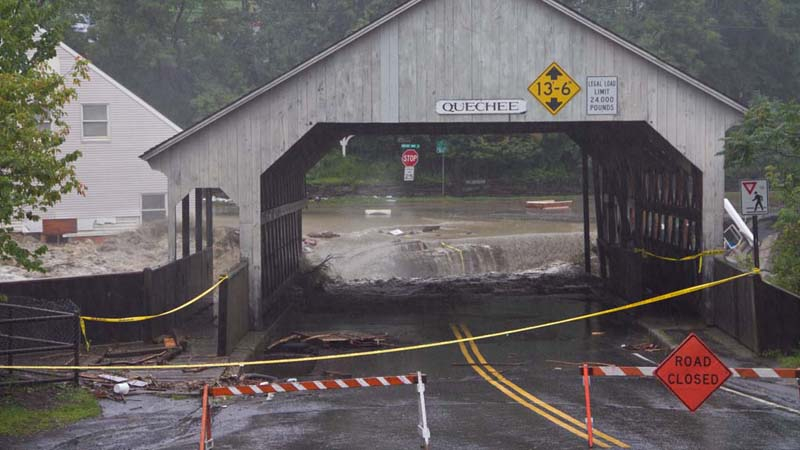 Flood waters from Tropical Storm Irene (2011-08-28) on the Ottauquechee River in Quechee, Vermont scouring the approach to the covered bridge on the northern shore of the river.