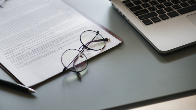 stock photo of eye glasses on a sheet of paper withe a laptop keyboard in the background