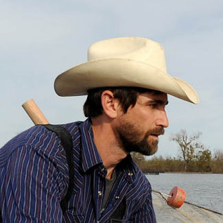 Jacob is wearing waders and pulling a seining net through shallow water.