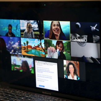 A zoom call with 10 visible attendees. Greta smiles as a student in the video below her holds something up to the camera.