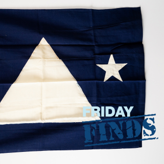 The flag of U.S. Coast and Geodetic Survey Director Rear Admiral Lee Otis Colbert. It is a blue field with a large white equilateral triangle in the center and two smaller stars on either side. The hoist has two brass grommets and is marked “DIRECTOR.FLAG. NO 2.”
