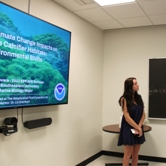 Alison stands next to a presentation title slide.
