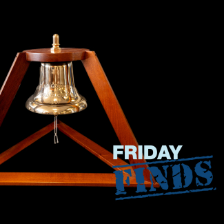 A photo of the bell from the USC&GS Ship Hydrographer. The bell hangs from a cherrywood pyramid-shaped frame.