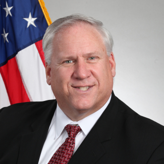 headshot of Jeffrey Thomas with American flag in the background