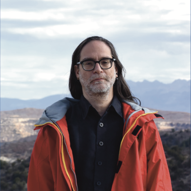 Dr. Sim Aberson stands in front of a beautiful vista with distant mountains in the background.